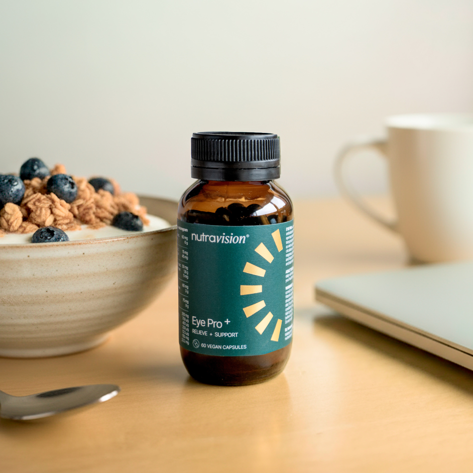 Bottle of Nutravita on a table with a bowl of cereal, cup, and laptop in the background.